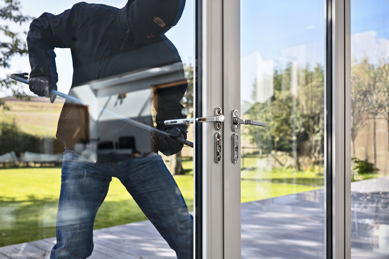 Burglar breaking into a house via a patio doors with a crowbar